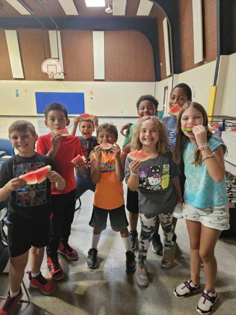 Kids posing in the gym with watermelon slices.