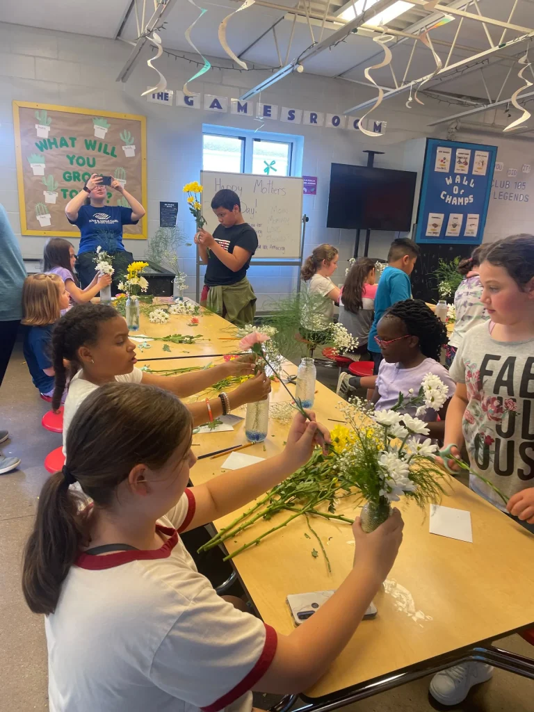 Kids putting floral arrangements together.