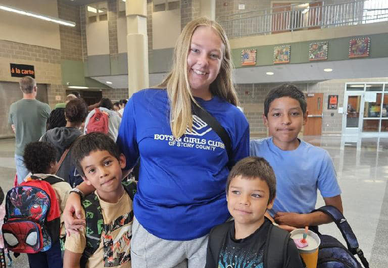 Staff member posing with kids in backpacks